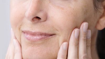Adult senior older woman touching perfect soft face skin with hand